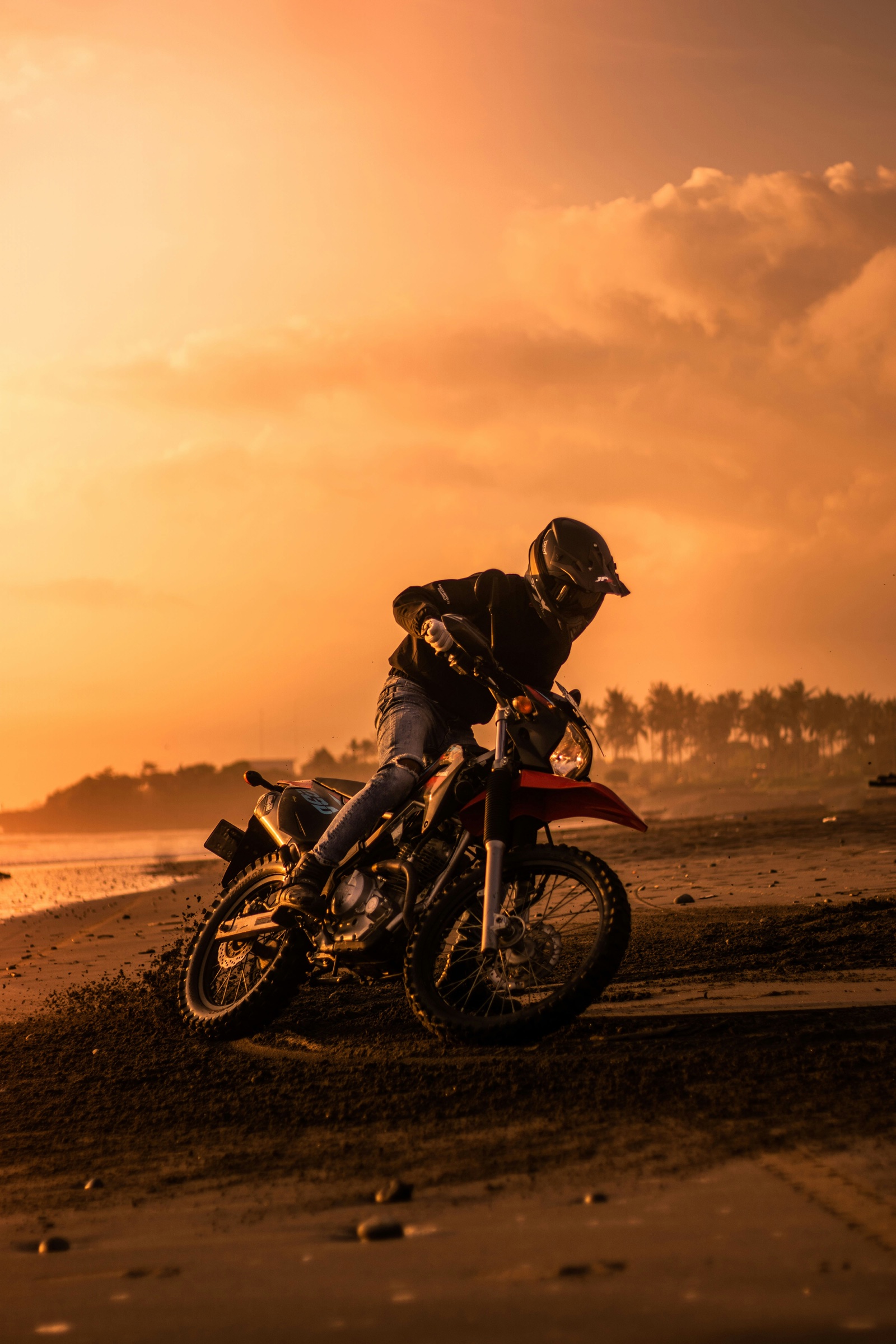 Enduro rider carving across sand at sunset